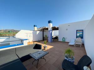 a patio with a table and chairs on a roof at Penthouse by the beach in Torrox Costa