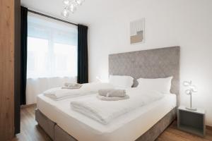 a bedroom with a large white bed with a large window at easy flat Villach main plaza in Villach