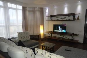 a living room with a white couch and a tv at Жетысу-3 дом 50 in Almaty