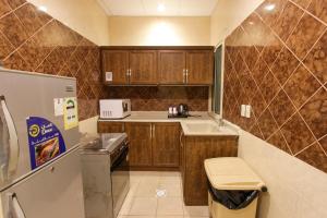 a small kitchen with wooden cabinets and a refrigerator at شقق مسكن الضيافة للشقق المخدومة 2 in Dammam +49 photos