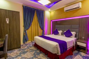 a bedroom with a bed with purple lights on it at شقق مسكن الضيافة للشقق المخدومة 2 in Dammam
