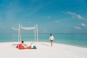 un homme et une femme assis sur une plage dans l'établissement Nova Maldives, à Dhangethi