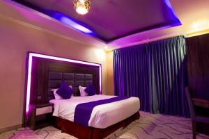 a bedroom with a large bed with purple lighting at Maskan Al Dyafah Hotel Apartments 2 in Dammam
