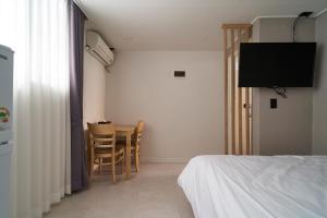 Un dormitorio con una cama, una mesa y un televisor. en Jinsim House in Hongdea, en Seúl