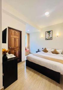 a bedroom with a large bed and a wooden door at Maplewood Hotel & Spa in Gangtok