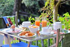 Hôtel Pietracap في باستيا: طاولة زجاجية عليها طعام ومشروبات للإفطار