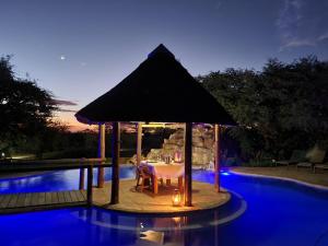 una mesa de comedor bajo una sombrilla junto a una piscina en Mattanu Private Game Reserve, en Barkly West