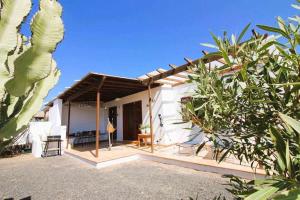 Casa blanca con patio con mesa y sillas en Cotton House, en Playa Blanca