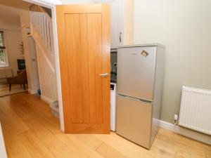 a wooden door in a kitchen next to a refrigerator at Potters Cottage in Sheffield