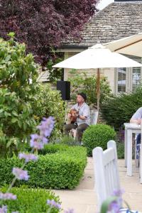 un homme assis sous un parasol dans un jardin dans l'établissement The Three Horseshoes, à Burford