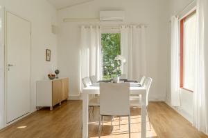 a white dining room with a white table and chairs at Tammikallio in Tjuda