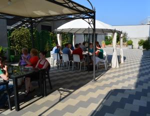 grupa ludzi siedzących przy stołach na patio w obiekcie Ilga Hotel w mieście Collecchio