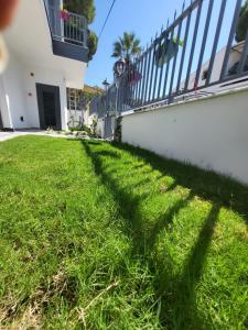 a shadow of a fence on the grass next to a house at Lulubay Rooms & Suites in Kusadası