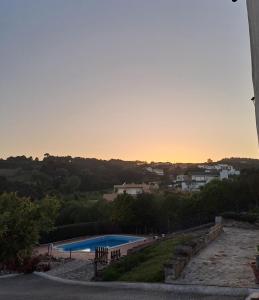 einen Pool mit Sonnenuntergang im Hintergrund in der Unterkunft Quinta da Fonte - Casa da Charrete in Caldas da Rainha