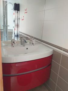 um lavatório vermelho e branco numa casa de banho em Maison Coquelicot em Saint-Georges-du-Bois