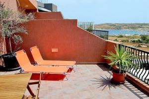 patio con sillas naranjas y balcón en Peaceful penthouse with views 3 min walk to the beach en Marsaskala