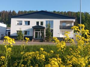 een wit huis met gele bloemen ervoor bij Heidenheimer Zimmer in Heidenheim an der Brenz