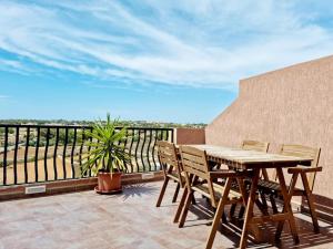 y balcón con mesa y sillas de madera. en Peaceful penthouse with views 3 min walk to the beach en Marsaskala