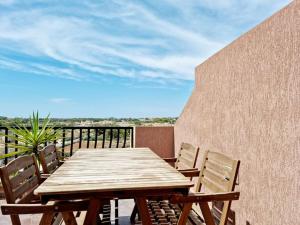 y balcón con mesa y sillas de madera. en Peaceful penthouse with views 3 min walk to the beach en Marsaskala