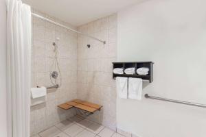 a bathroom with a shower with a toilet and towels at Howard Johnson by Wyndham National City/San Diego South in National City