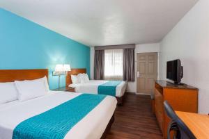 a hotel room with two beds and a flat screen tv at Howard Johnson by Wyndham National City/San Diego South in National City