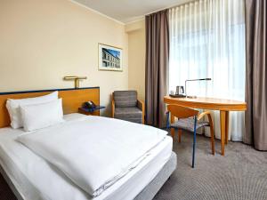 a hotel room with a bed and a desk at Mercure Hotel Düsseldorf City Center in Düsseldorf