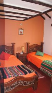 two beds in a room with orange walls at Casa Villa de Leyva in Villa de Leyva