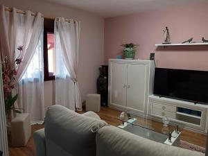 een woonkamer met een bank en een tv bij A Cavadiña in Vilaboa