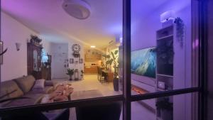 uma sala de estar com um sofá e uma televisão em Home way from home em Netanya