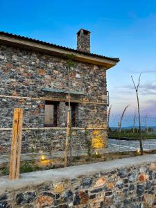 an old stone house with a fence in front of it at Modern Stone Villas with Swimming Pool in Aliveri