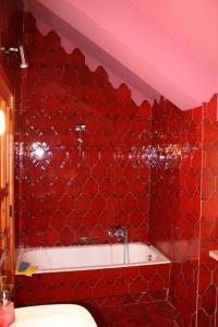 La salle de bains rouge est pourvue d'une baignoire et d'un mur en carrelage rouge. dans l'établissement Lo Chalet della antica Locomotiva, à Camigliatello Silano