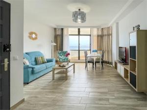 uma sala de estar com um sofá azul e uma mesa em Beachfront Apartment incl highspeed WIFI em Melenara