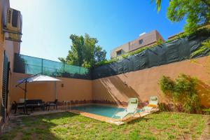 Villa Targa في مراكش: حديقة خلفية مع مسبح مع كراسي ومظلة