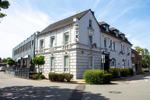 Un edificio blanco con un cartel al costado. en Airport Hotel Jägerhof Weeze, en Weeze