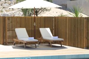 two lounge chairs and an umbrella next to a pool at Domaine du Ferret Restaurant & Spa in Cap-Ferret