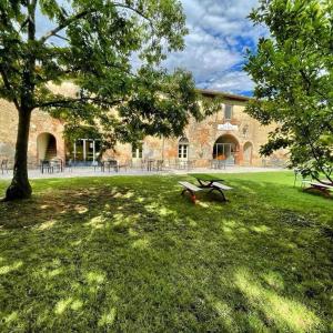 a building with a tree in the grass in front of it at Tenuta La Fratta in Sinalunga