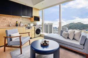 een woonkamer met een bank en stoelen en een keuken bij Doubletree By Hilton Shenzhen Airport Residences in Shenzhen