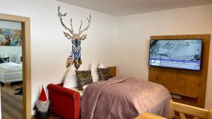 Appartements by Hofer في كابرون: غرفة نوم بسرير وتلفزيون على جدار