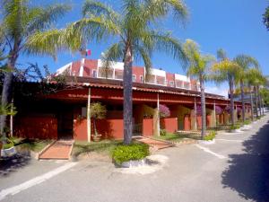 un edificio rojo con palmeras delante en Residence Hotel Felix en Ricadi