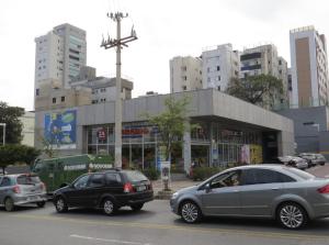 a busy city street with cars parked in front of a store at Apto enorme varanda reformado Mater Dei e hospitais in Belo Horizonte