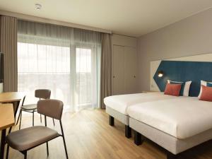 a hotel room with a large bed and a desk at Aparthotel Adagio Antwerp City Center in Antwerp