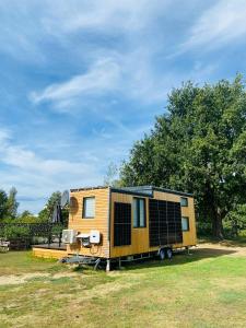 una casita amarilla estacionada en un campo en Tiny House im Spreewald en Kittlitz