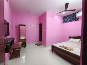 a bedroom with pink walls and a bed and a sink at Le Paradise Inn in Pondicherry