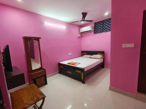 a bedroom with pink walls and a bed and a mirror at Le Paradise Inn in Pondicherry