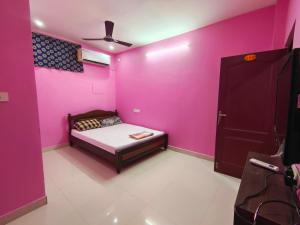 um quarto com uma cama e uma parede rosa em Le Paradise Inn em Pondicherry