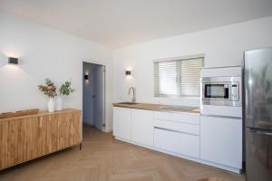 La cuisine est équipée de placards blancs et d'un réfrigérateur en acier inoxydable. dans l'établissement Appartement James, à Jan Thiel