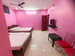 Habitación rosa con 2 camas y silla en Le Paradise Inn en Pondicherry