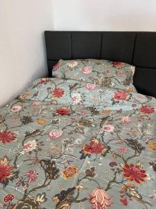 a bed with a floral comforter on it at City Appartement direkt am Schloss! in Karlsruhe