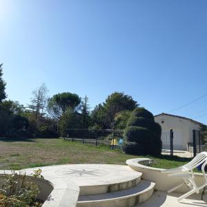 eine Terrasse mit zwei weißen Stühlen und einer Bank in der Unterkunft Maison Coquelicot in Saint-Georges-du-Bois