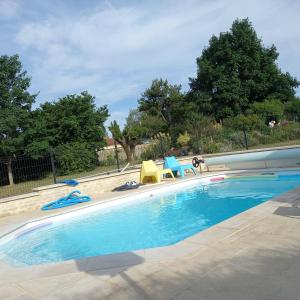 a swimming pool with two chairs and two chairs at Maison Coquelicot in Saint-Georges-du-Bois